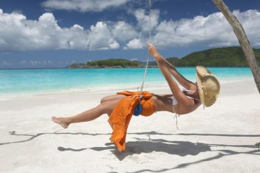 woman swinging on beautiful beach in the carribean Top 10 Things To Do in Antigua feat