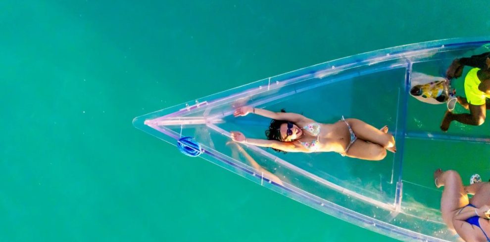 happy girl laying on glass boat rock adventures antigua tour feat Reef Explorers Transparent Glass Boat And Beach Tour